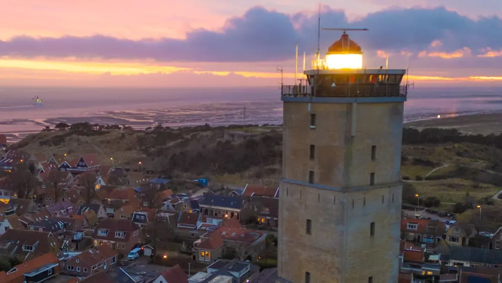 De Brandaris in West-Terschelling bij zonsondergang, met de daken van het dorp eromheen