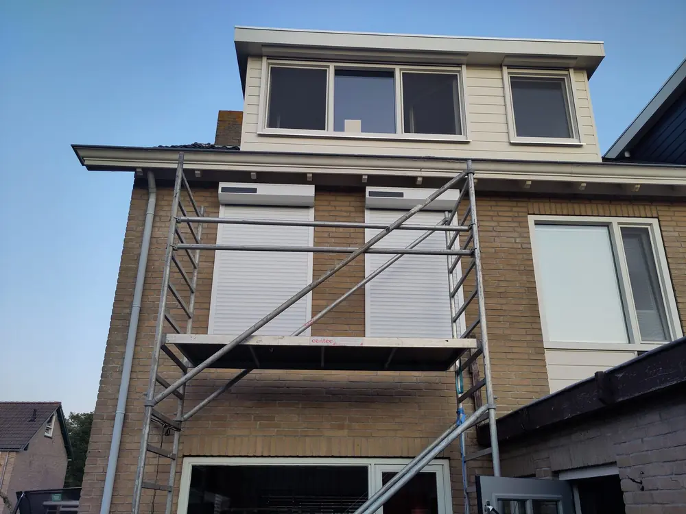 Steiger met net geïnstalleerde Somfy rolluiken op de gevel van een woning